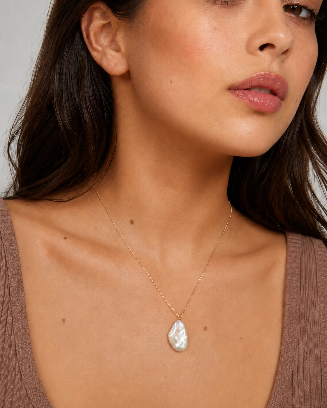 Baroque pearl pendant necklace worn with a delicate gold-tone chain